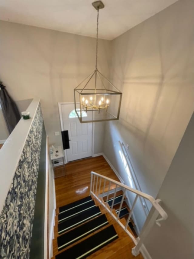 staircase with wood-type flooring and a notable chandelier