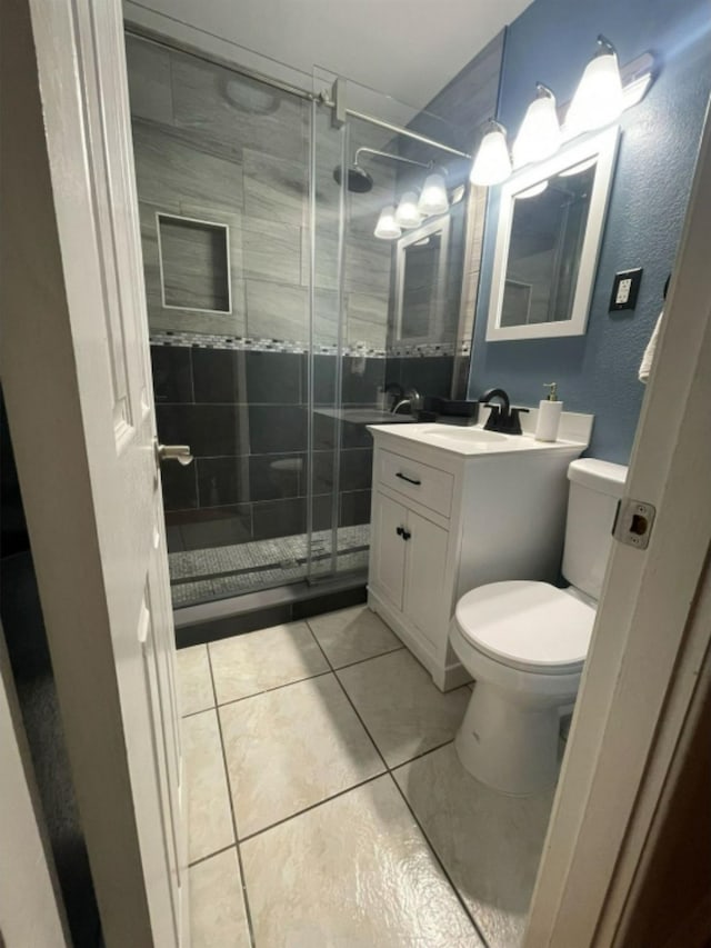 bathroom featuring toilet, an enclosed shower, vanity, and tile patterned floors