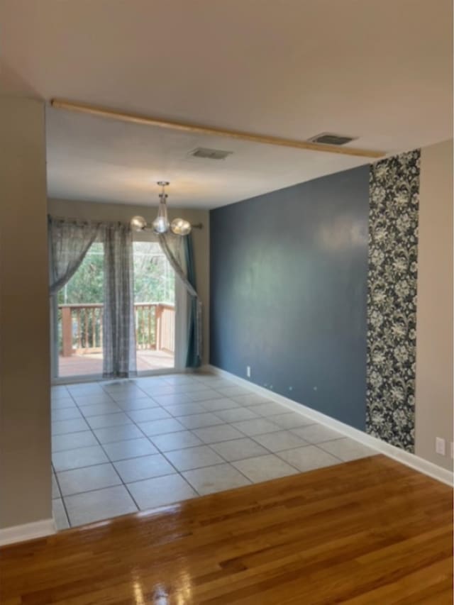 empty room with light hardwood / wood-style floors and a chandelier