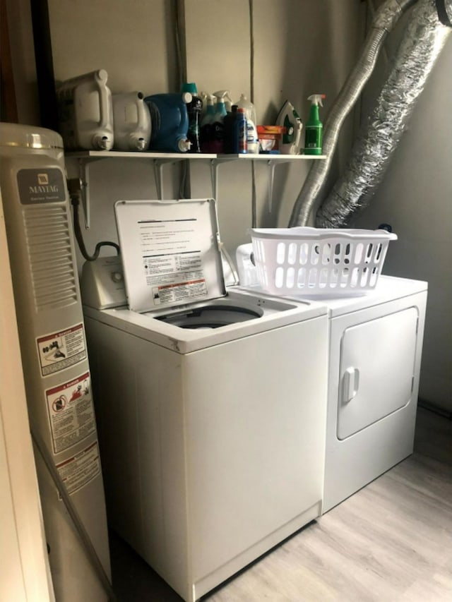 laundry room featuring washing machine and clothes dryer, light hardwood / wood-style floors, and water heater