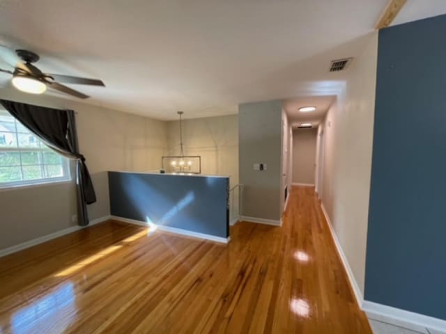 unfurnished room with hardwood / wood-style flooring and ceiling fan with notable chandelier
