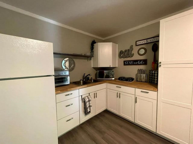 kitchen featuring butcher block counters, sink, white cabinets, dark wood-type flooring, and white refrigerator