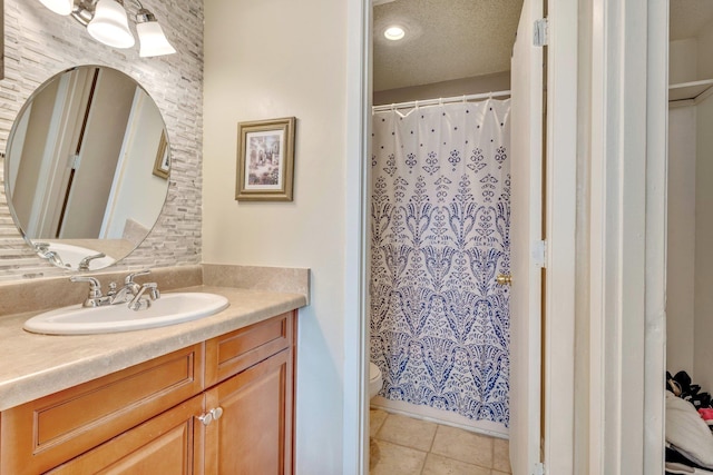 bathroom featuring tile patterned flooring, vanity, a textured ceiling, and toilet