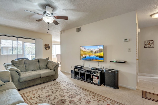 living room featuring ceiling fan, light colored carpet, and a textured ceiling