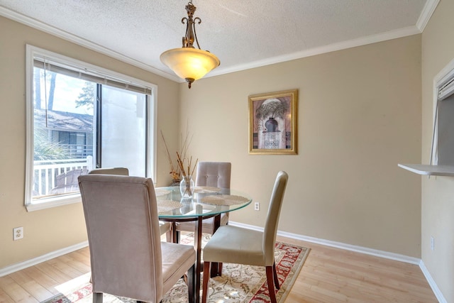 dining space with ornamental molding, a healthy amount of sunlight, and light wood-type flooring