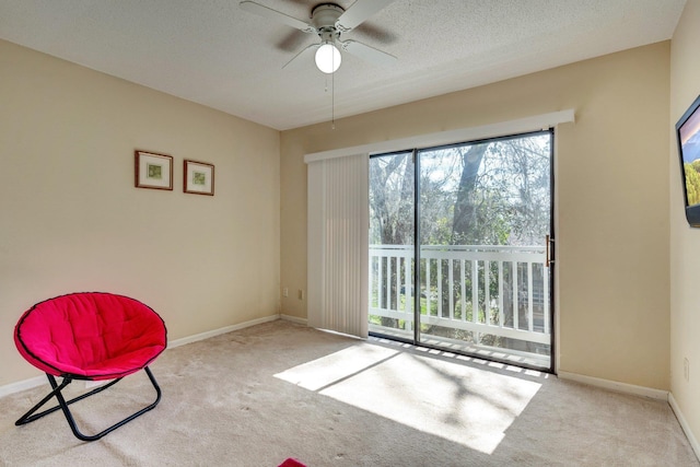 sitting room featuring ceiling fan, light colored carpet, and a textured ceiling