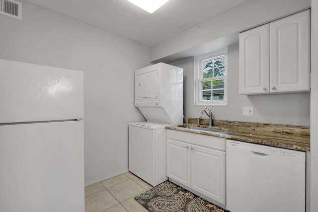 washroom featuring light tile patterned floors, stacked washing maching and dryer, and sink