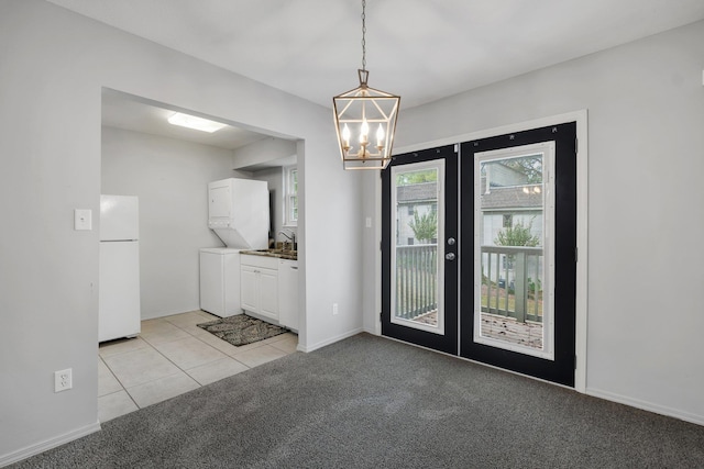 carpeted entrance foyer with a chandelier, sink, and french doors