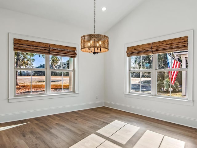 unfurnished dining area featuring hardwood / wood-style floors, lofted ceiling, and a notable chandelier