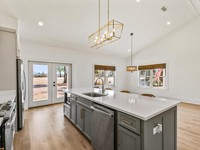 kitchen featuring gray cabinets, a center island with sink, decorative light fixtures, and stainless steel appliances