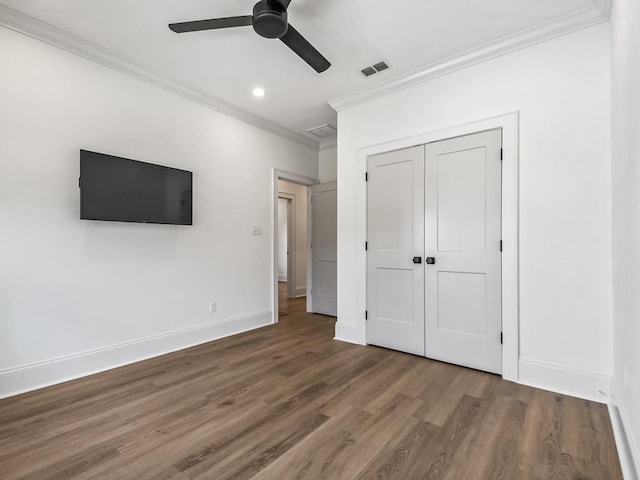 unfurnished bedroom featuring crown molding, dark hardwood / wood-style floors, a closet, and ceiling fan