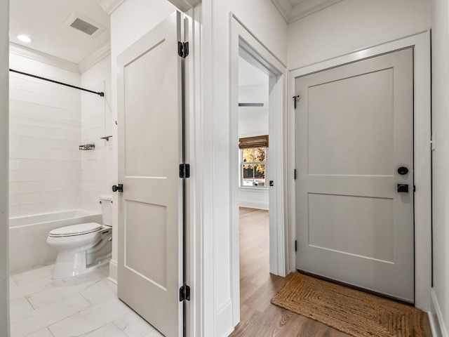 bathroom with wood-type flooring, shower / bathtub combination, toilet, and ornamental molding