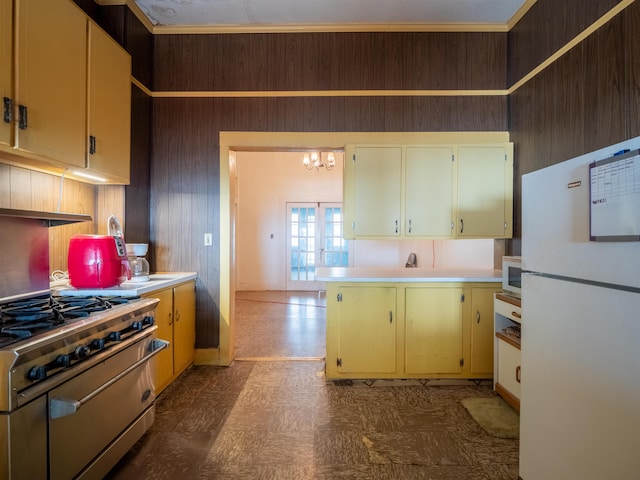 kitchen featuring appliances with stainless steel finishes, crown molding, a notable chandelier, and wood walls