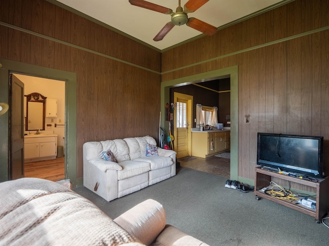 living room with carpet, wood walls, sink, and ceiling fan