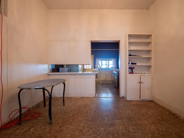 kitchen with white cabinets, kitchen peninsula, and stainless steel range