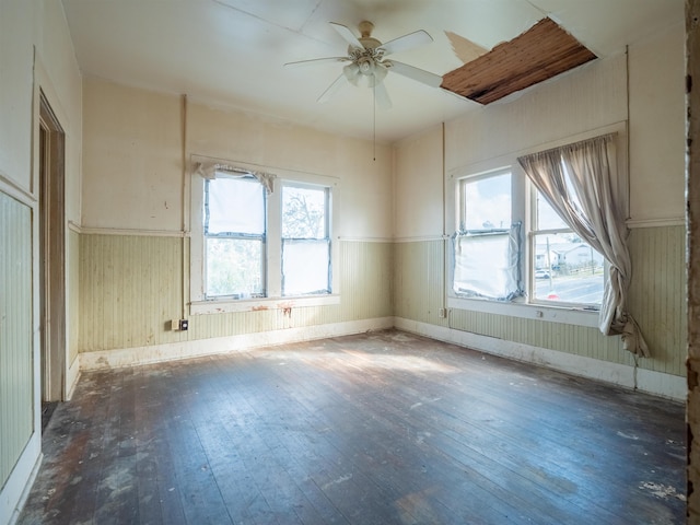 spare room featuring dark hardwood / wood-style floors, ceiling fan, and wooden walls