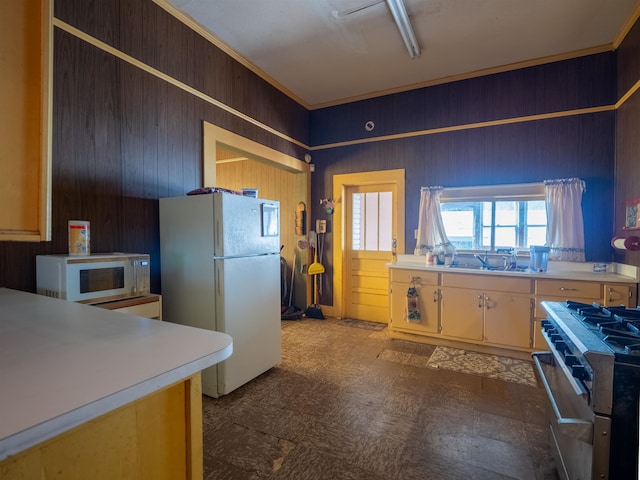 kitchen featuring white appliances, wooden walls, and sink