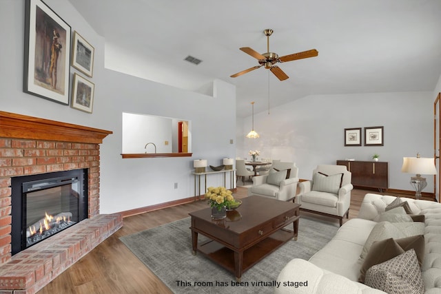 living room featuring ceiling fan, lofted ceiling, dark wood-type flooring, and a fireplace