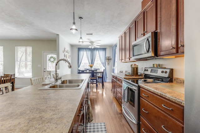 10446 Rose Rd, Tallahassee, FL 32311 - kitchen with light countertops, appliances with stainless steel finishes, a sink, decorative light fixtures, and wood-type flooring