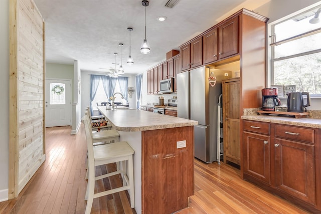 10446 Rose Rd, Tallahassee, FL 32311 - kitchen with light countertops, light wood-style flooring, a kitchen bar, appliances with stainless steel finishes, and an island with sink