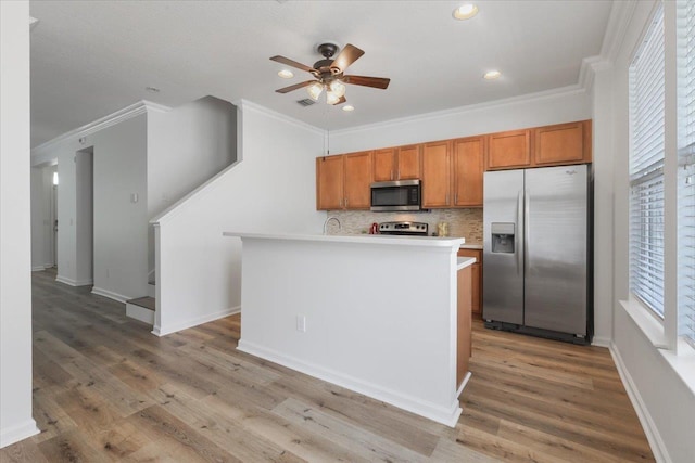 4312 Four Oaks Blvd, Tallahassee, FL 32311 - kitchen with appliances with stainless steel finishes, a ceiling fan, brown cabinets, crown molding, and backsplash