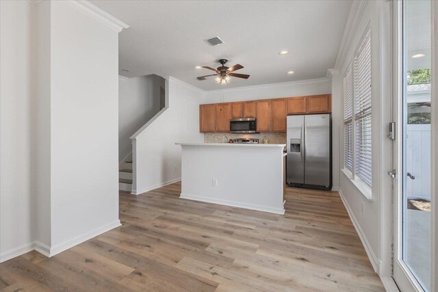 4312 Four Oaks Blvd, Tallahassee, FL 32311 - kitchen featuring appliances with stainless steel finishes, brown cabinets, backsplash, light wood finished floors, and ornamental molding