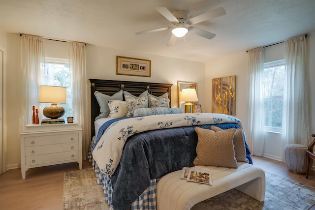 bedroom featuring ceiling fan, multiple windows, and light hardwood / wood-style flooring