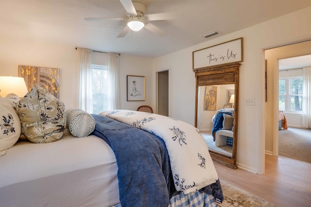 bedroom with multiple windows, light hardwood / wood-style floors, and ceiling fan