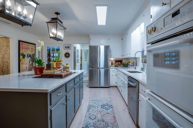 kitchen featuring white cabinetry, appliances with stainless steel finishes, decorative light fixtures, and sink