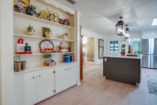 kitchen featuring white cabinetry, light wood-type flooring, stainless steel fridge, a kitchen island, and pendant lighting