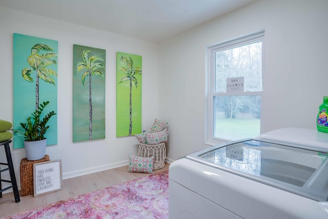 laundry area with washing machine and clothes dryer and light hardwood / wood-style floors