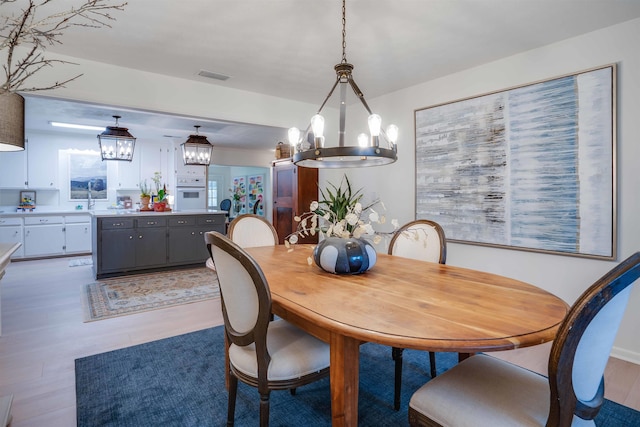 dining area featuring light hardwood / wood-style floors and a chandelier