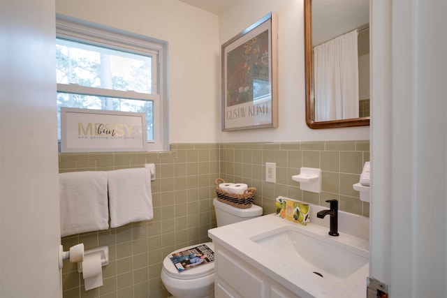 bathroom with vanity, toilet, and tile walls