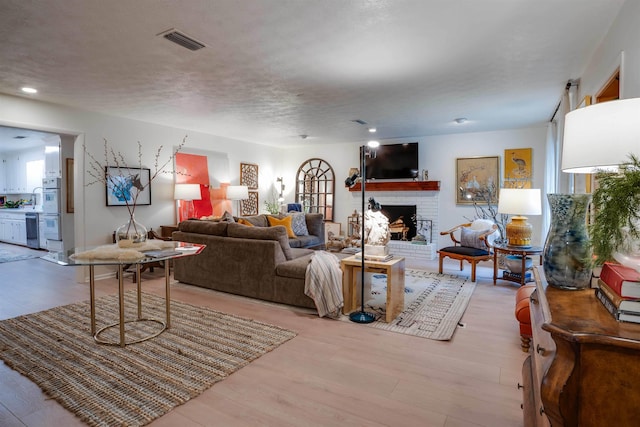 living room with a fireplace, light hardwood / wood-style flooring, and a textured ceiling