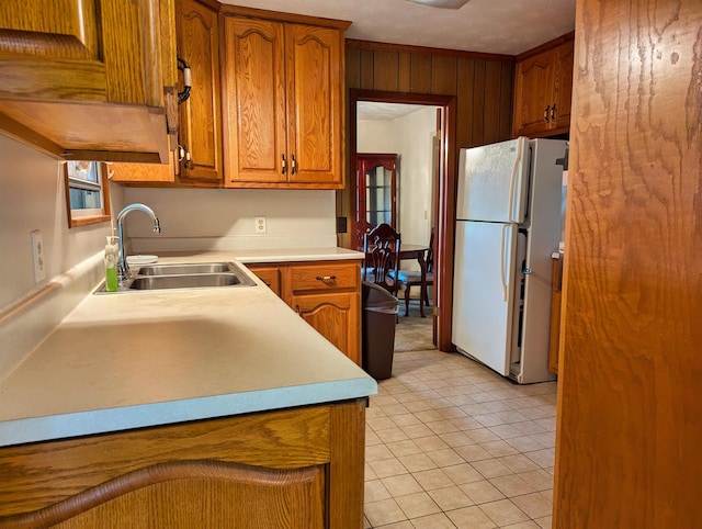 kitchen featuring wooden walls, sink, white refrigerator, and light tile patterned floors