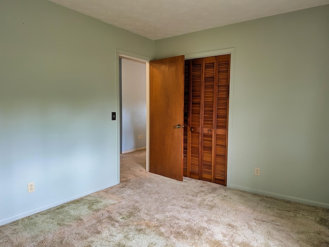 unfurnished bedroom featuring light carpet, a closet, and a textured ceiling