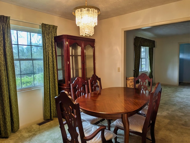 carpeted dining room featuring a textured ceiling and an inviting chandelier