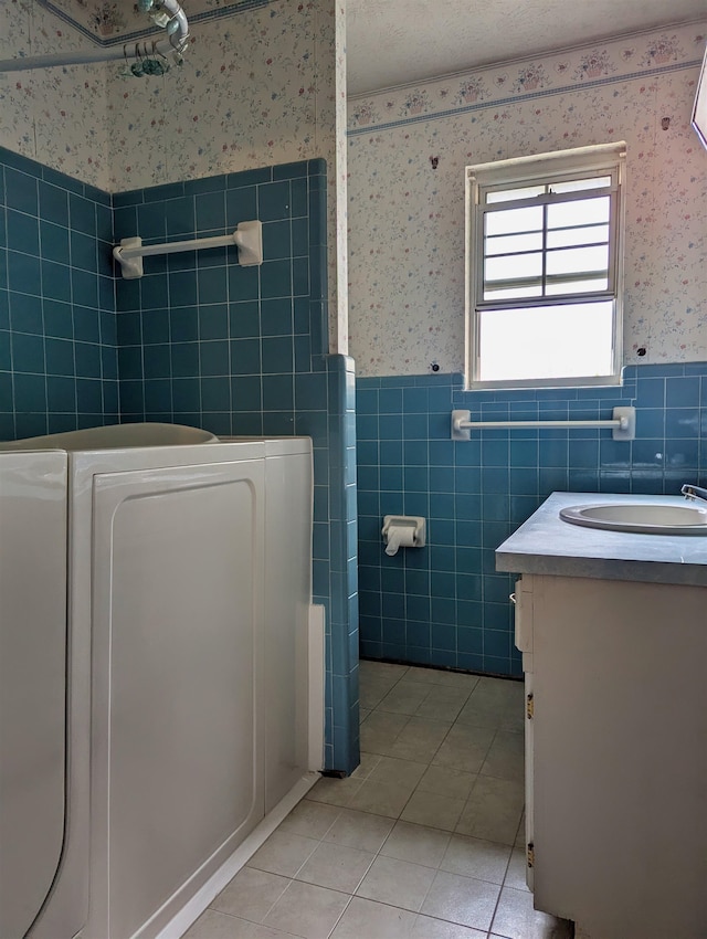 bathroom featuring tile walls, a tub to relax in, vanity, and tile patterned floors