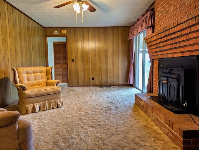 carpeted living room with wooden walls, a wood stove, ceiling fan, and a textured ceiling