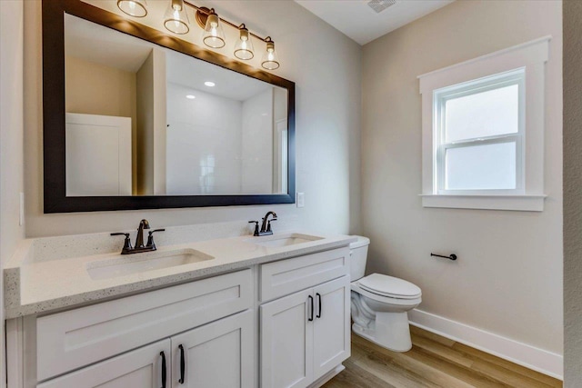 bathroom featuring hardwood / wood-style flooring, vanity, walk in shower, and toilet