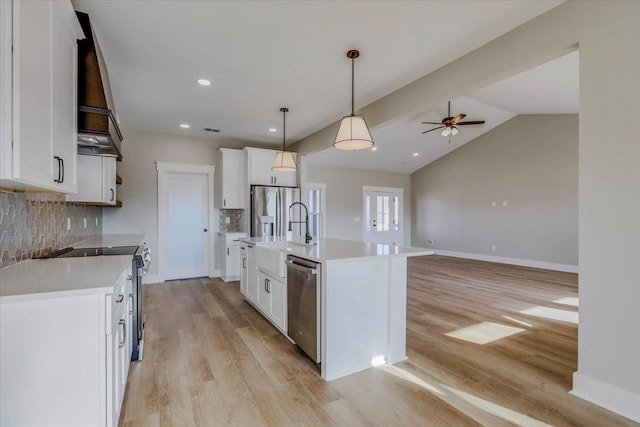 kitchen with light hardwood / wood-style flooring, appliances with stainless steel finishes, white cabinetry, hanging light fixtures, and an island with sink