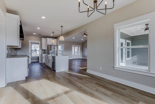 kitchen with hanging light fixtures, an island with sink, dark hardwood / wood-style flooring, and white cabinetry