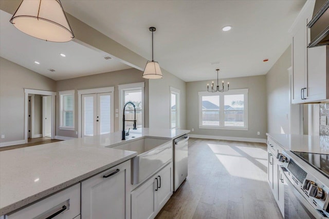 kitchen with white cabinetry, light stone counters, and pendant lighting