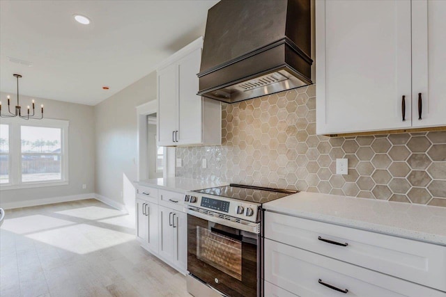 kitchen with white cabinetry, stainless steel electric range oven, custom range hood, pendant lighting, and light stone countertops