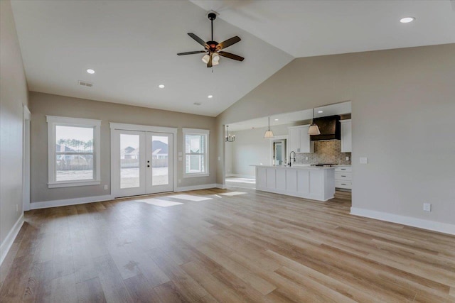 unfurnished living room featuring french doors, sink, high vaulted ceiling, ceiling fan, and light hardwood / wood-style floors