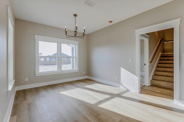 unfurnished dining area with a chandelier and light hardwood / wood-style floors