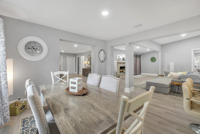 dining room with a stone fireplace and light hardwood / wood-style floors