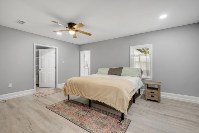 bedroom with ceiling fan, ensuite bath, and light hardwood / wood-style flooring