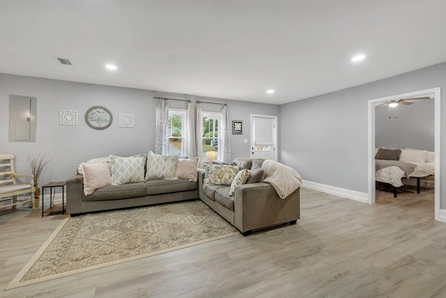 living room featuring electric panel, ceiling fan, and light wood-type flooring