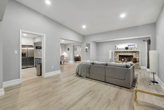 living room featuring lofted ceiling, a fireplace, and light hardwood / wood-style flooring